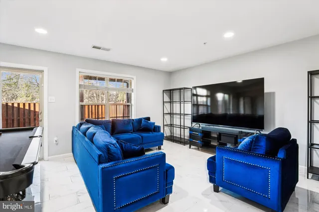 a living room with furniture pool table flat screen tv and windows