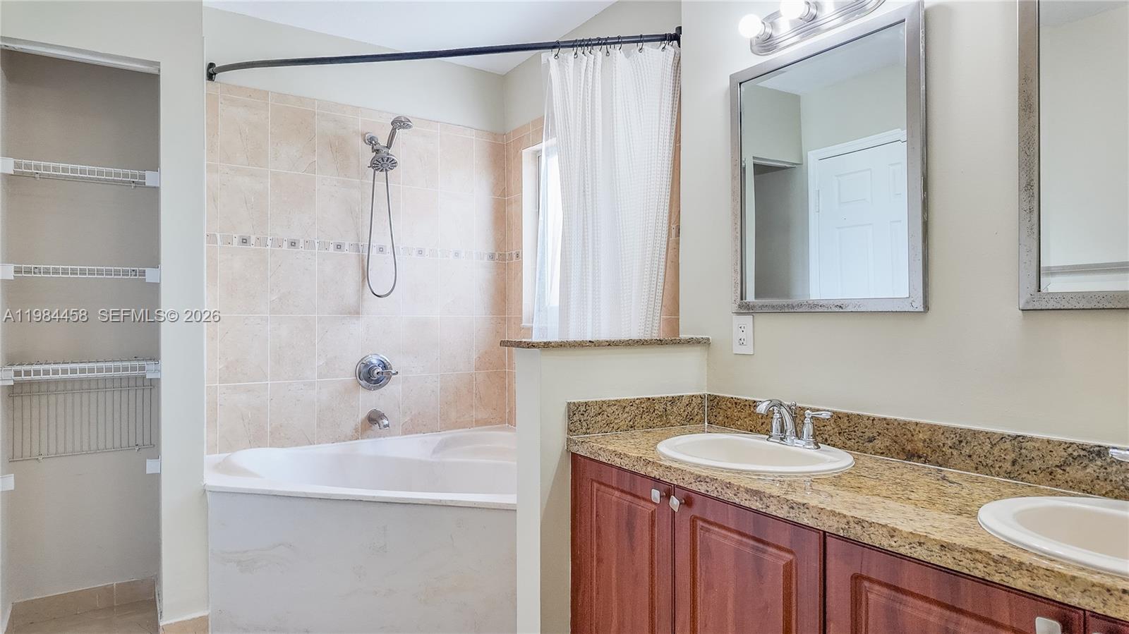 6002 Southwest 8th Street, Unit 3 West Miami, FL 33144 - Photo 7 of 10 a bathroom with a granite countertop sink a mirror a shower and a bathtub