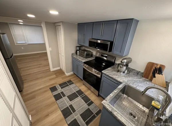 a kitchen with granite countertop stainless steel appliances a stove refrigerator sink and microwave