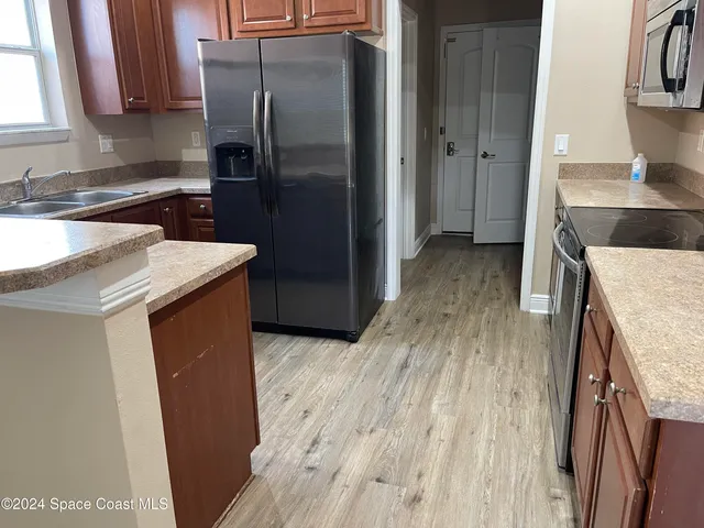 a kitchen that has a sink a refrigerator and a stove top oven