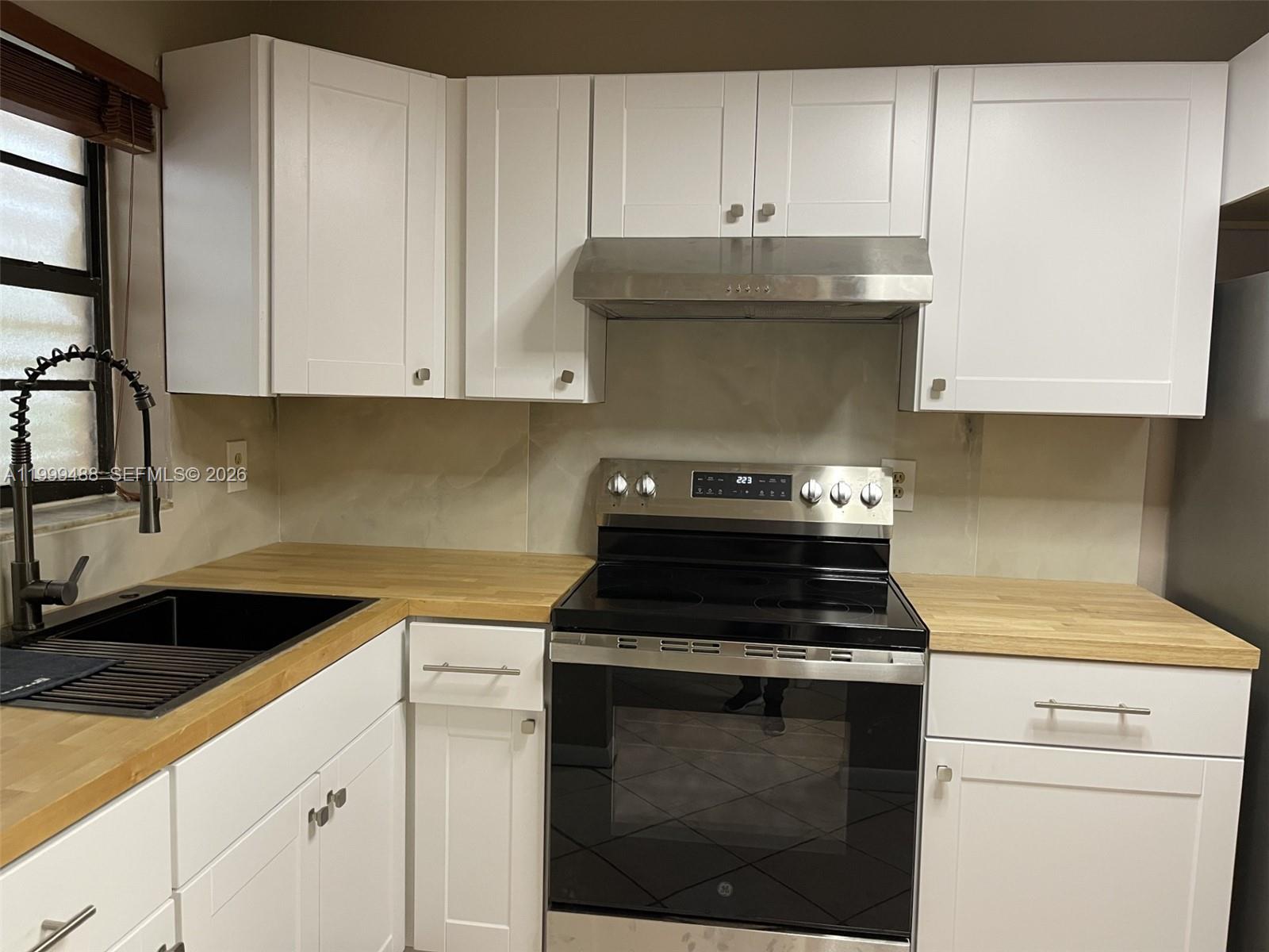 1250 Lincoln Road, Unit 306 Miami Beach, FL 33139 - Photo 4 of 12 a kitchen with granite countertop white cabinets and a stove