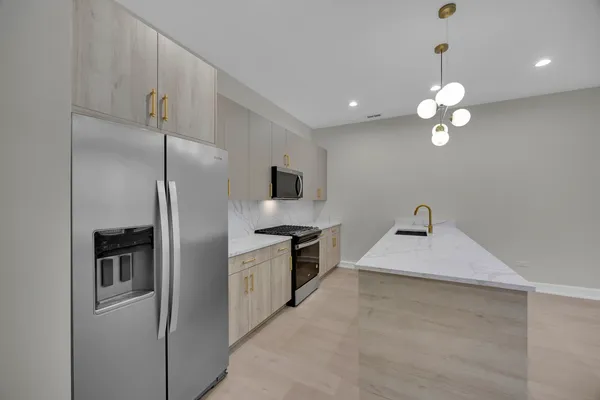 a kitchen with stainless steel appliances granite countertop a sink a refrigerator and a granite counter tops