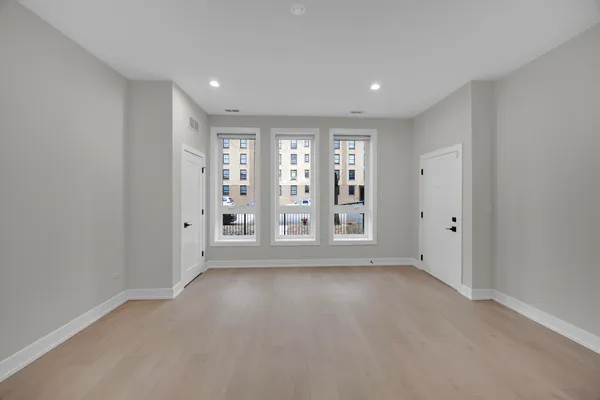 a view of an empty room with a window and wooden floor