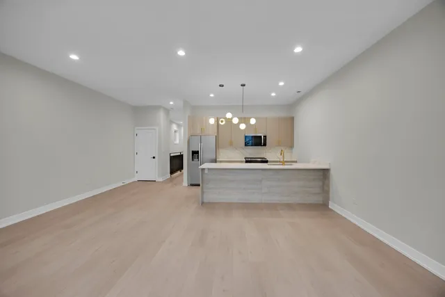 a view of large kitchen with kitchen island a sink stainless steel appliances and white cabinets