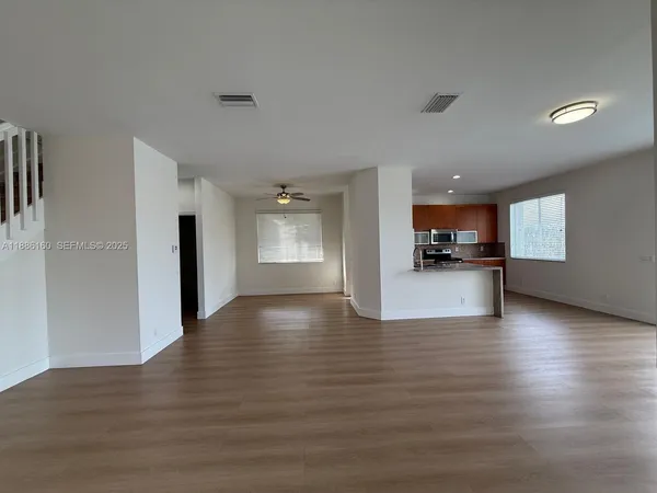 a view of empty room with kitchen and window