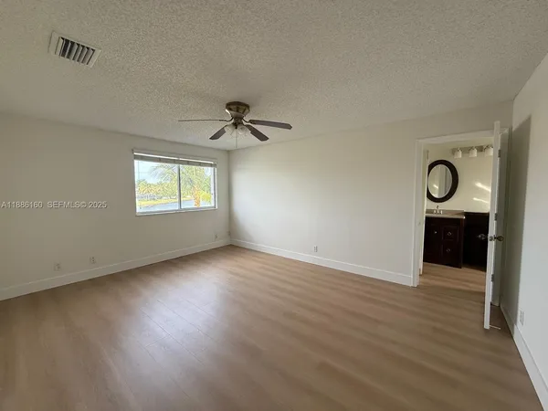 an empty room with wooden floor closet and windows