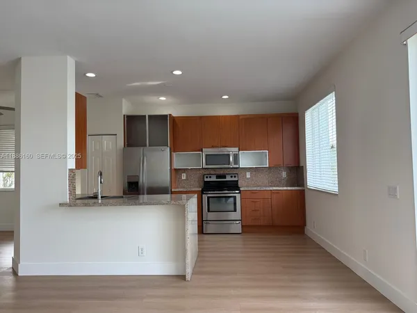 a kitchen with stainless steel appliances kitchen island granite countertop a stove a sink and a refrigerator