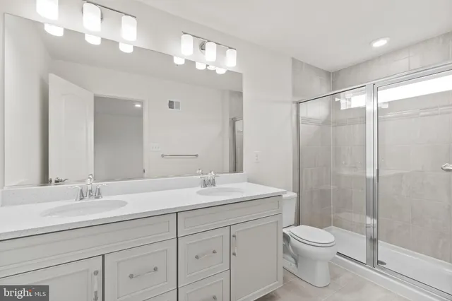 a bathroom with a toilet a sink a mirror a shower a vanity and window