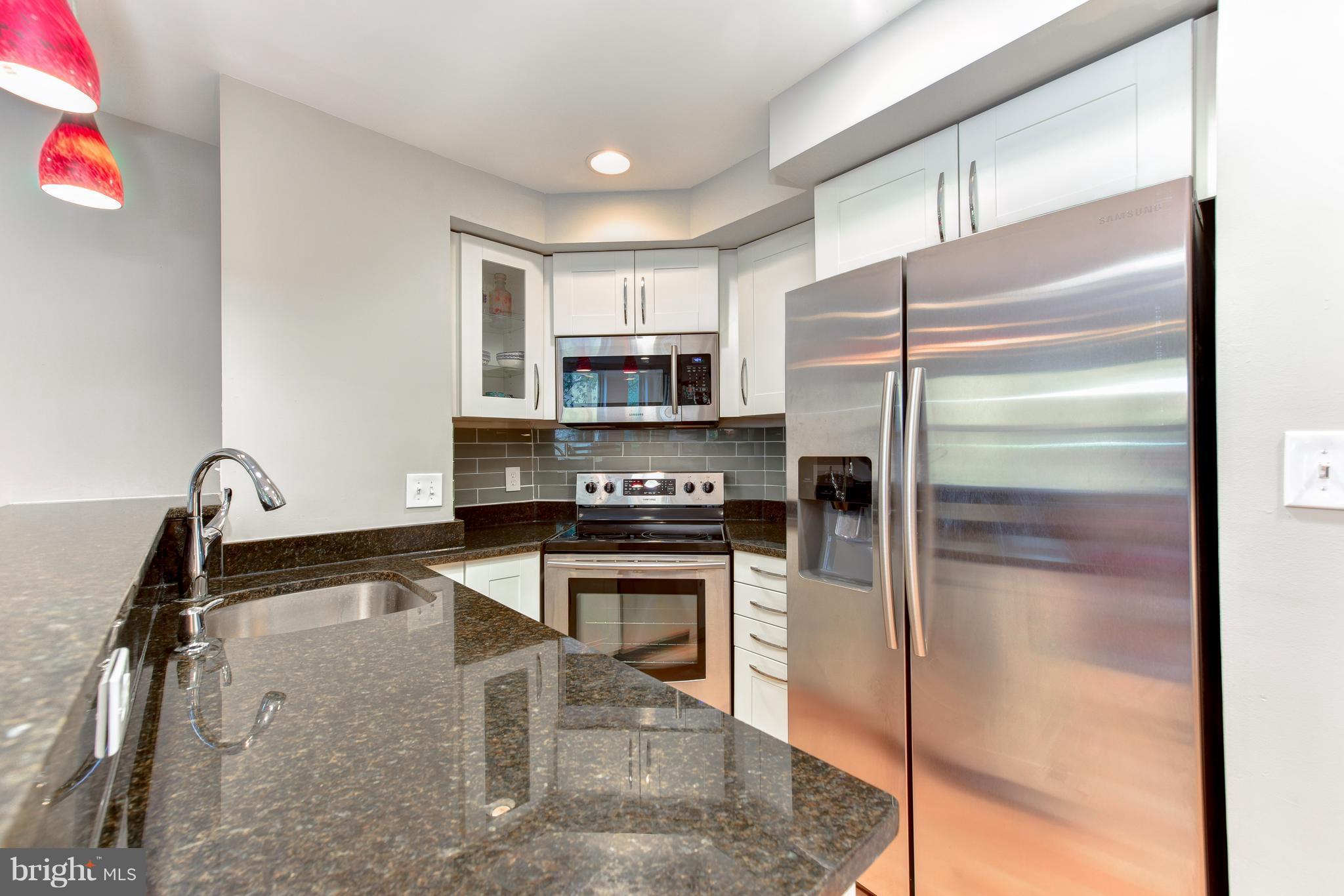 2440 16th Street Northwest, Unit 412 Washington, DC 20009 - Photo 14 of 25 a kitchen with granite countertop a refrigerator and a sink