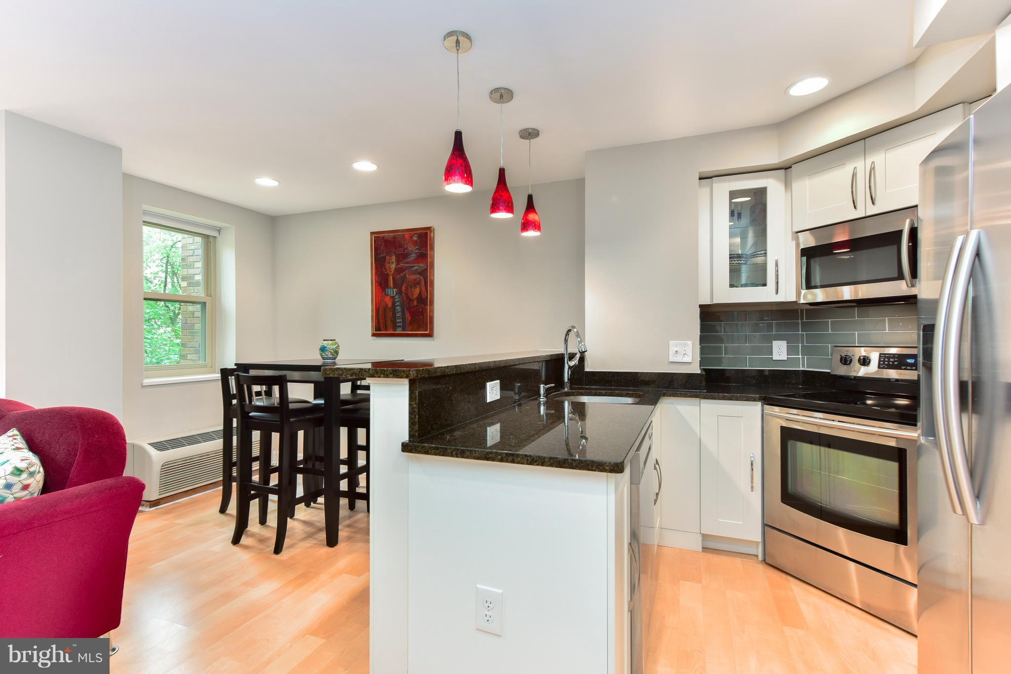 2440 16th Street Northwest, Unit 412 Washington, DC 20009 - Photo 7 of 25 a kitchen with stainless steel appliances granite countertop a stove a microwave a dining table and chairs