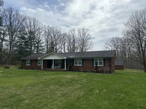 a view of a house with a yard and large trees