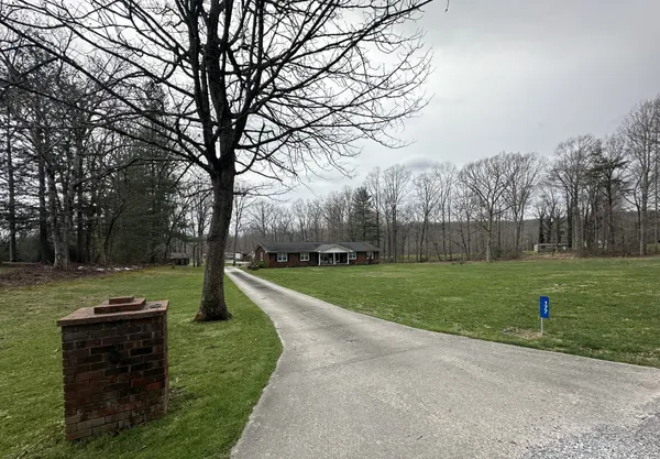 a view of a house with a big yard and large trees