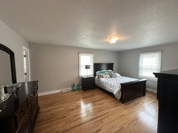a spacious bedroom with a bed and wooden floor