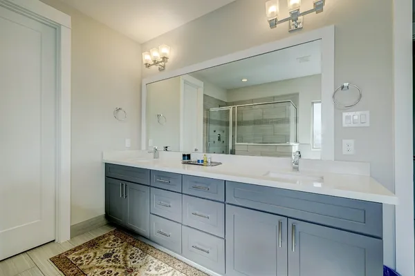 a bathroom with double vanity and a mirror