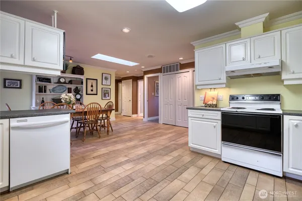 a kitchen with stainless steel appliances kitchen island granite countertop a stove top oven a sink a dining table and chairs with wooden floor