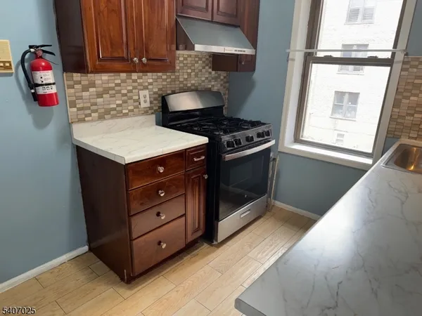 a kitchen with stainless steel appliances granite countertop a stove a sink and a microwave