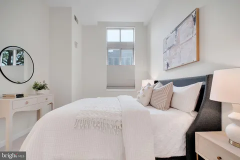 a bedroom with a bed a mirror and windows