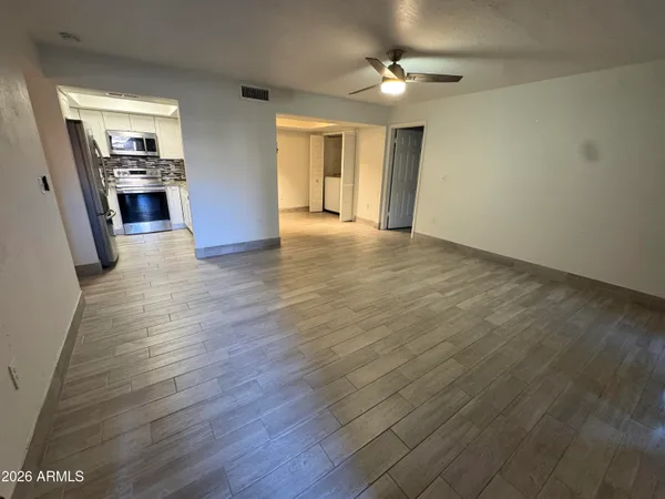 an empty room with wooden floor and ceiling fan