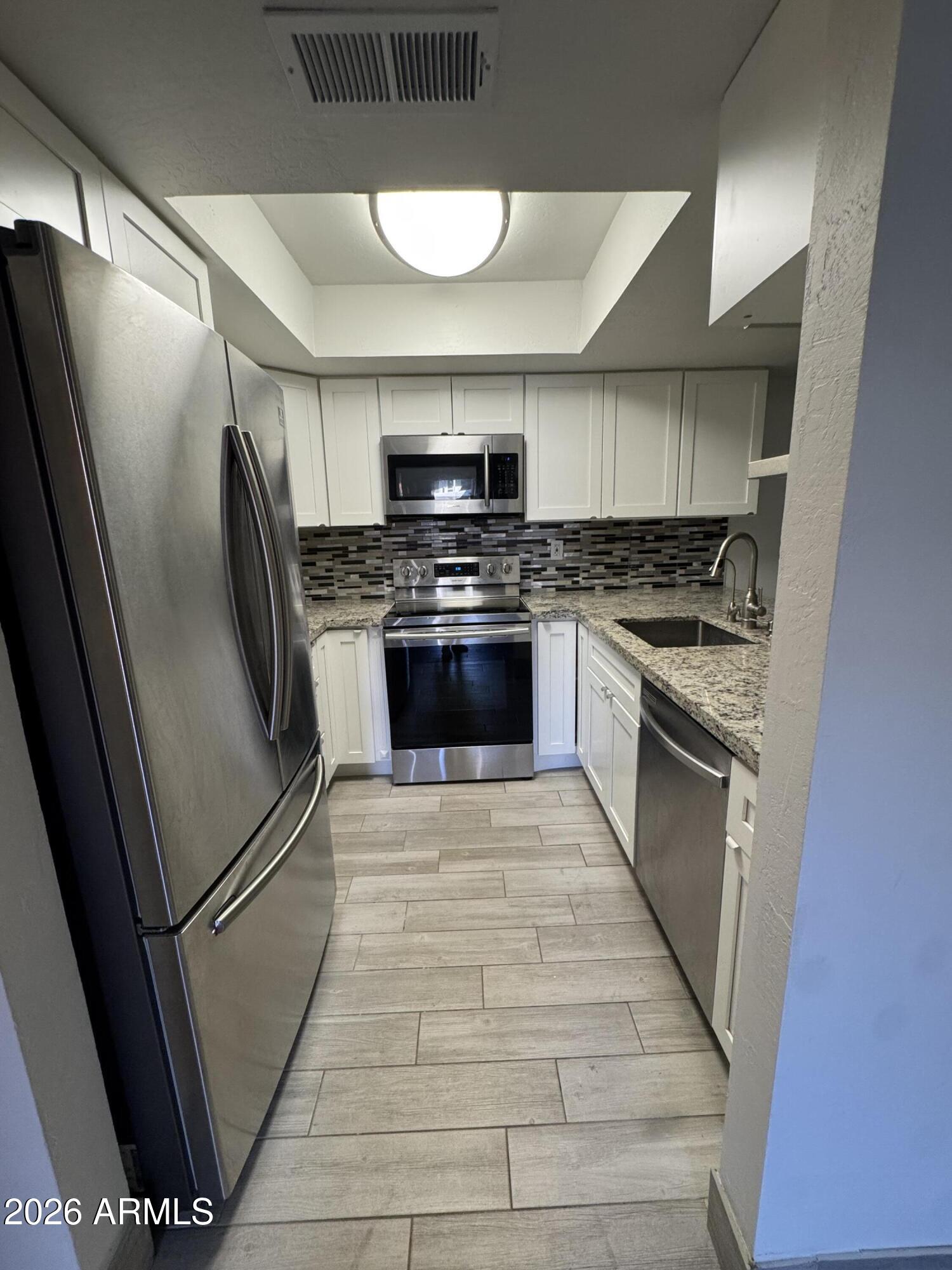1645 West Baseline Road, Unit 1187 Mesa, AZ 85202 - Photo 4 of 16 a kitchen with stainless steel appliances granite countertop a stove a refrigerator and a stove