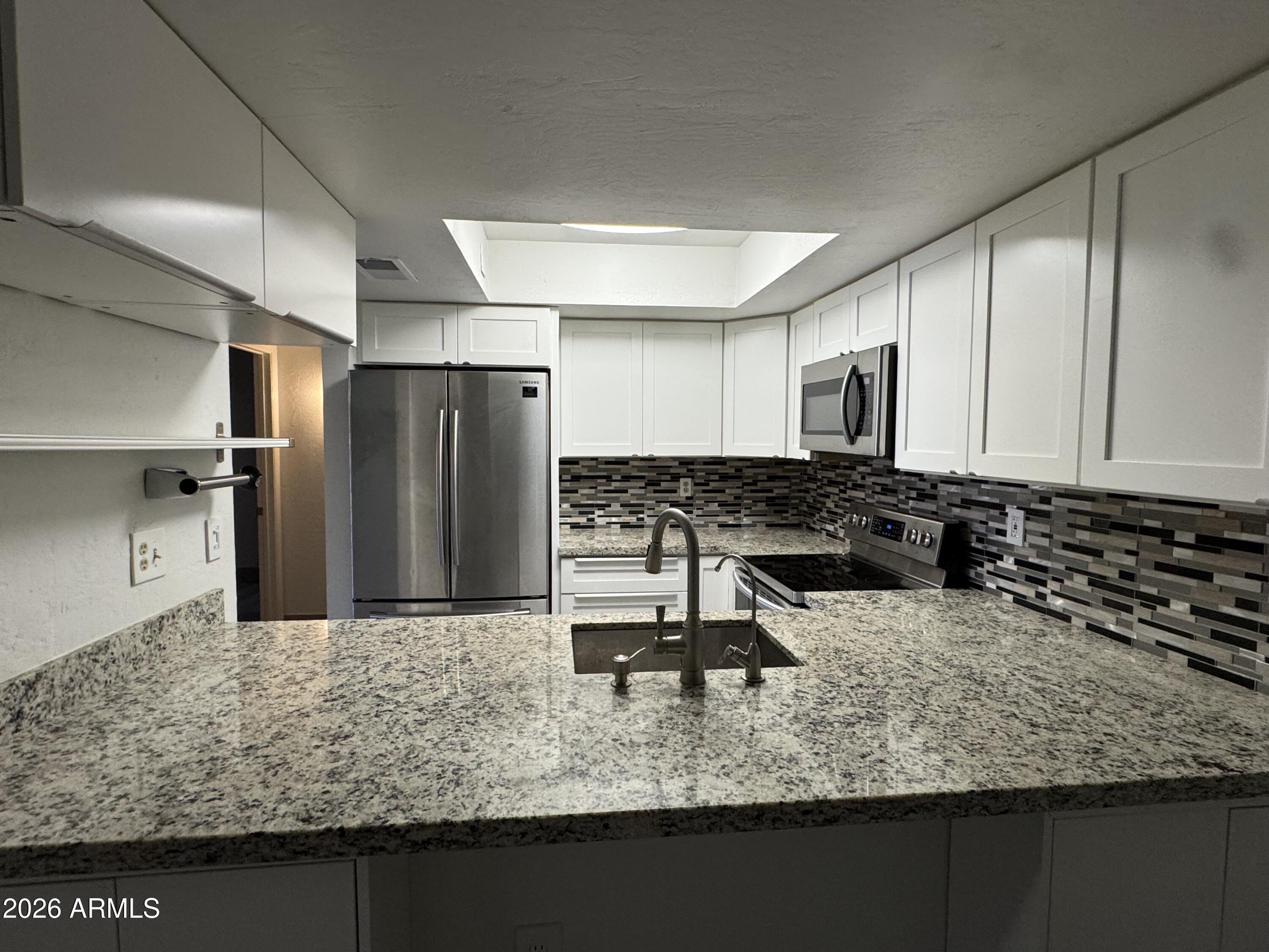 1645 West Baseline Road, Unit 1187 Mesa, AZ 85202 - Photo 5 of 16 a kitchen with a sink refrigerator and microwave
