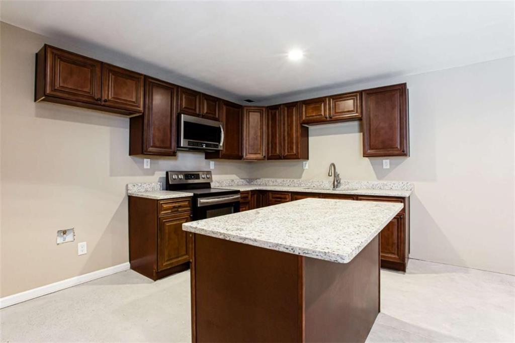 3721 Bogan Mill Road Northeast Buford, GA 30519 - Photo 45 of 58 a kitchen with granite countertop a sink and a stove top oven