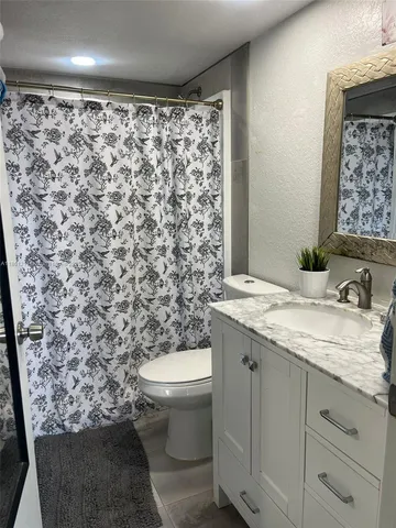 a bathroom with a granite countertop sink and a toilet