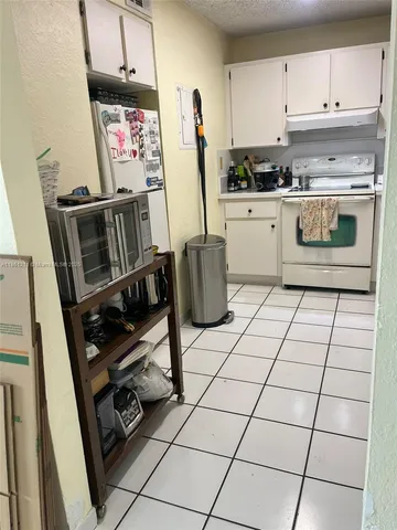a kitchen with granite countertop a stove a sink and a refrigerator