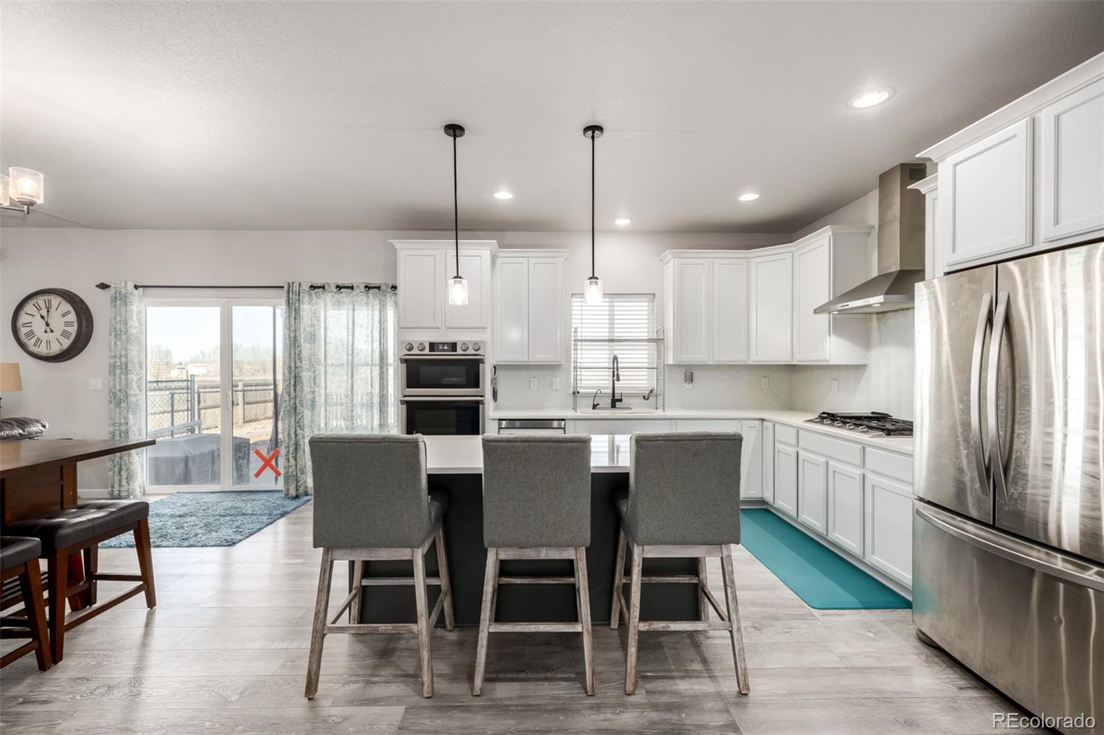 1875 Rancher Drive Milliken, CO 80543 - Photo 11 of 50 a kitchen with stainless steel appliances granite countertop a stove a refrigerator a kitchen island a table and chairs