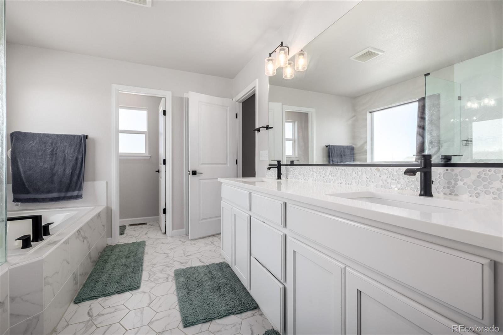 1875 Rancher Drive Milliken, CO 80543 - Photo 18 of 50 a spacious bathroom with a double vanity sink a mirror a vanity and shower