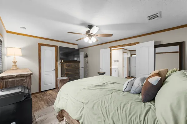 a bedroom with a large bed a flat tv screen and a ceiling fan