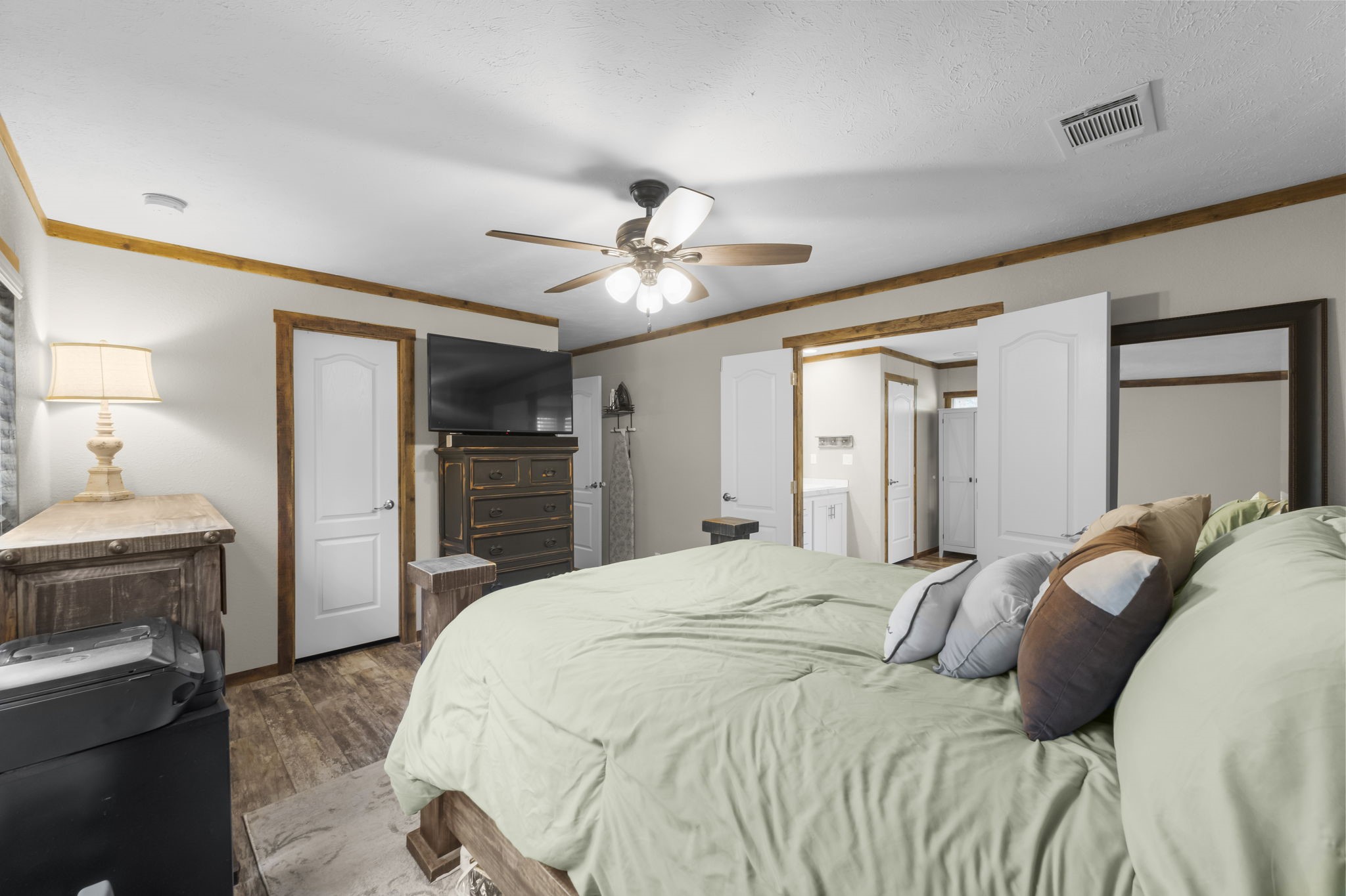 577 Winding River Road South Oakhurst, TX 77359 - Photo 17 of 31 a bedroom with a large bed a flat tv screen and a ceiling fan