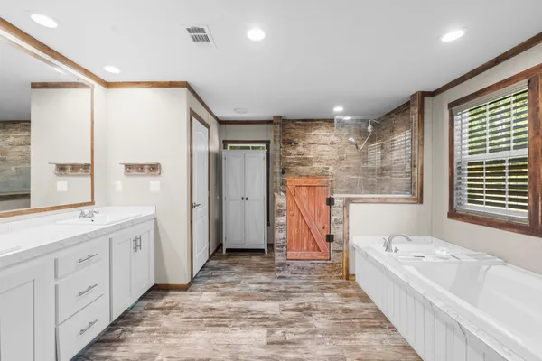 a bathroom with a tub sink shower and mirror