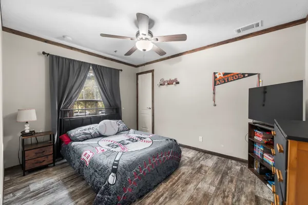 a bedroom with a bed dresser and a flat tv screen