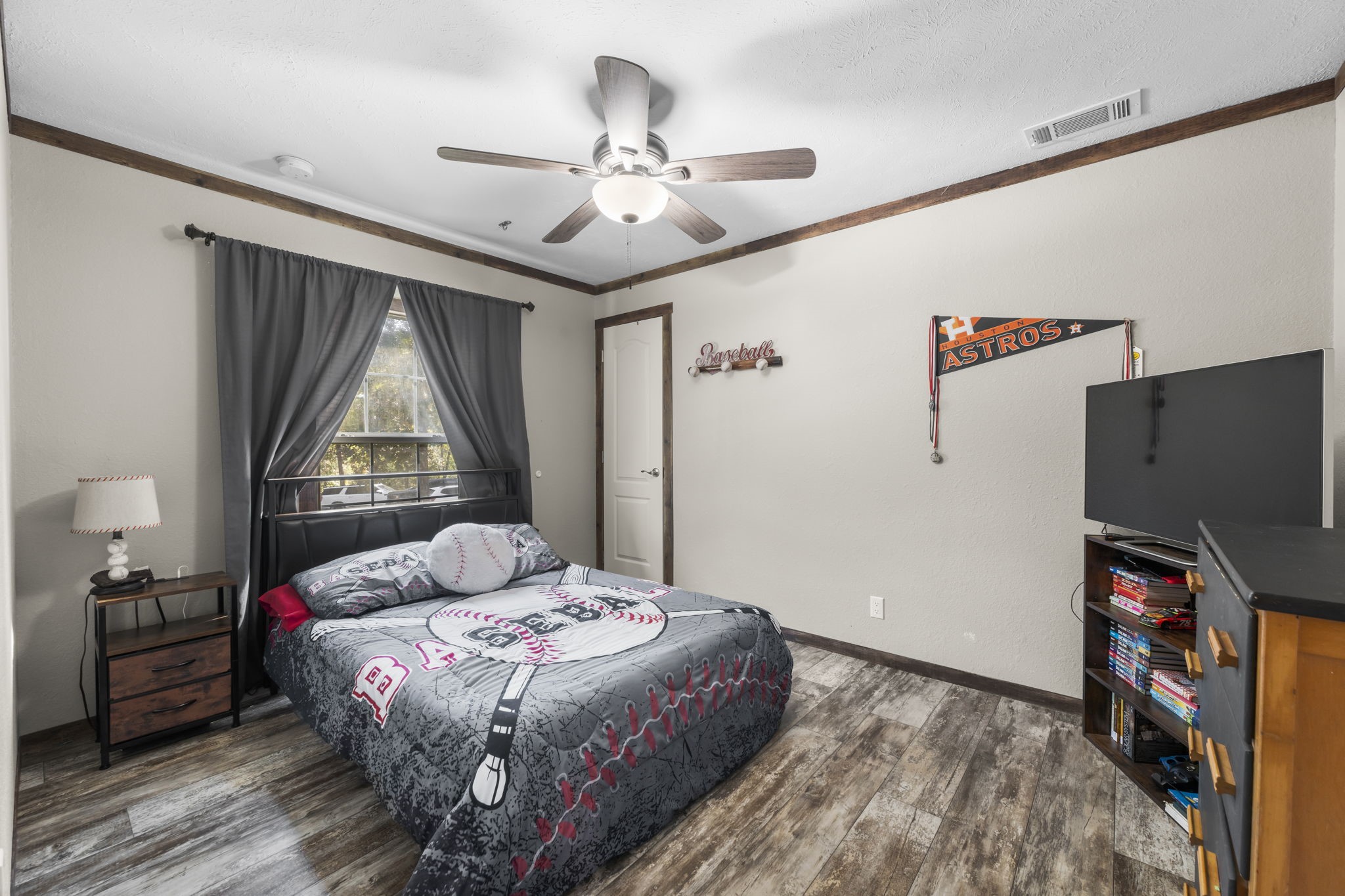 577 Winding River Road South Oakhurst, TX 77359 - Photo 21 of 31 a bedroom with a bed dresser and a flat tv screen