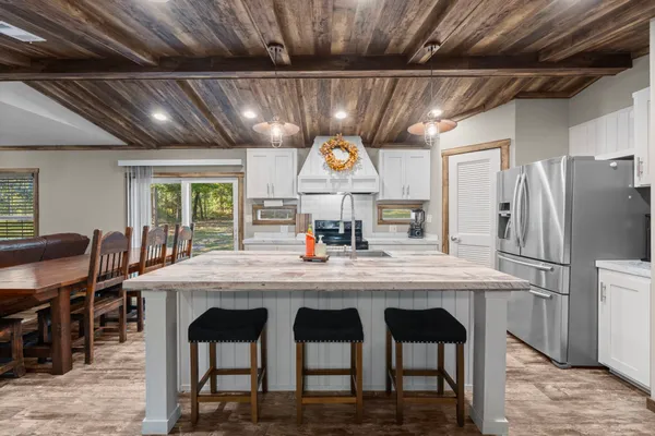 a kitchen with stainless steel appliances granite countertop a table chairs and a refrigerator