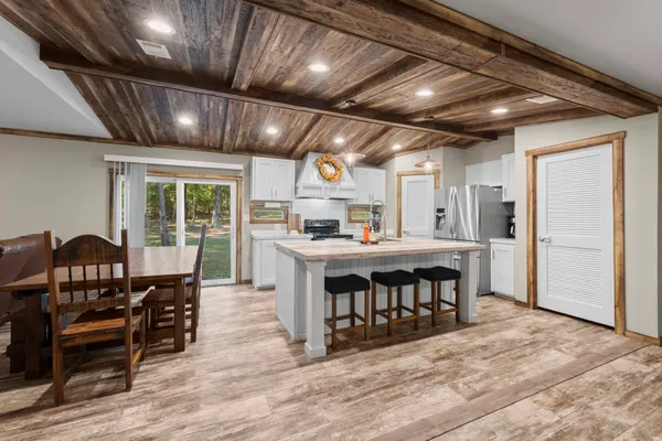 a large kitchen with stainless steel appliances granite countertop a stove a refrigerator a dining table and chairs with wooden floor