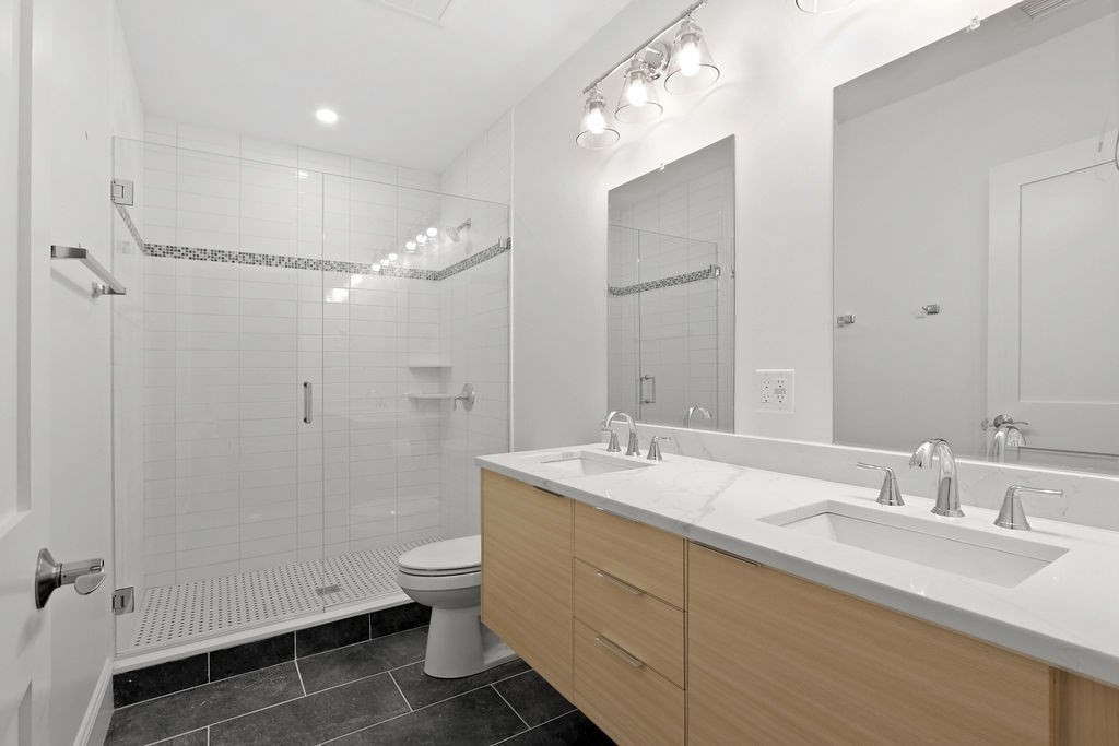 21 Glen Road, Unit 5 Boston, MA 02130 - Photo 6 of 11 a bathroom with a double vanity sink toilet mirror and shower