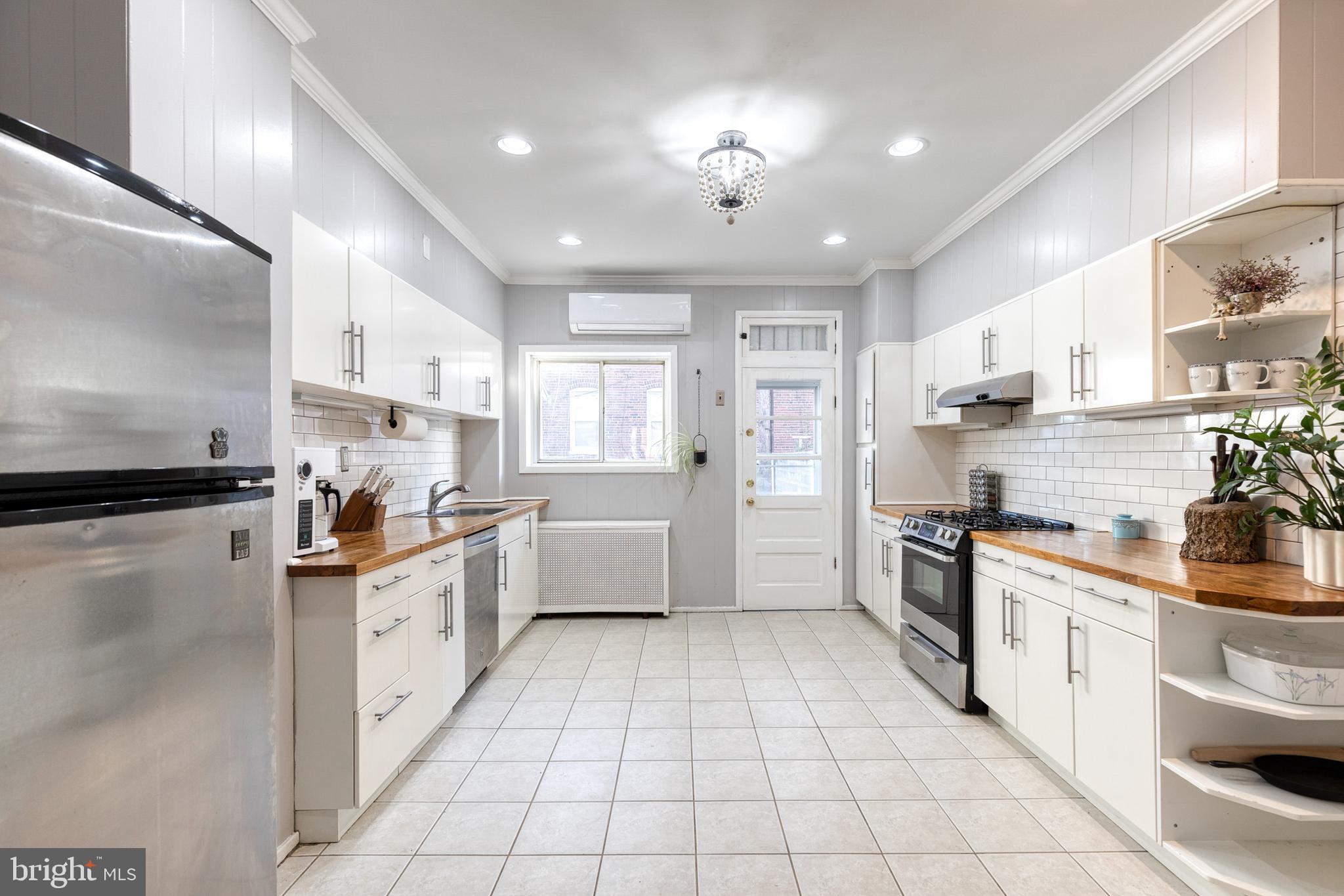 3903 Hudson Street Baltimore, MD 21224 - Photo 12 of 34 a kitchen with stainless steel appliances kitchen island granite countertop a sink a stove top oven and white cabinets