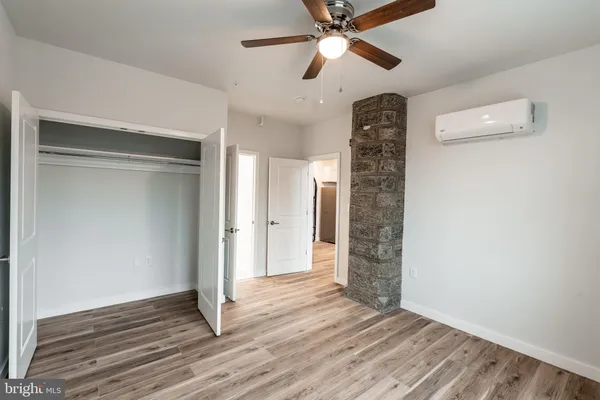 a view of an empty room with wooden floor and a ceiling fan