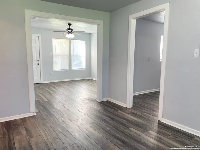 an empty room with wooden floor and windows