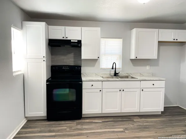 a kitchen with granite countertop white cabinets and stainless steel appliances