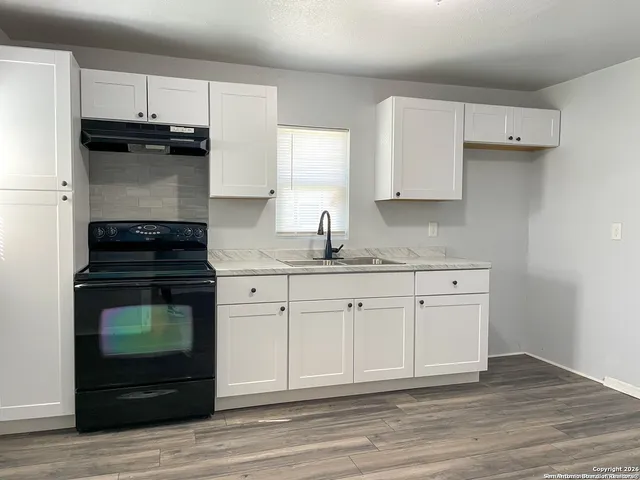 a kitchen with granite countertop white cabinets and stainless steel appliances