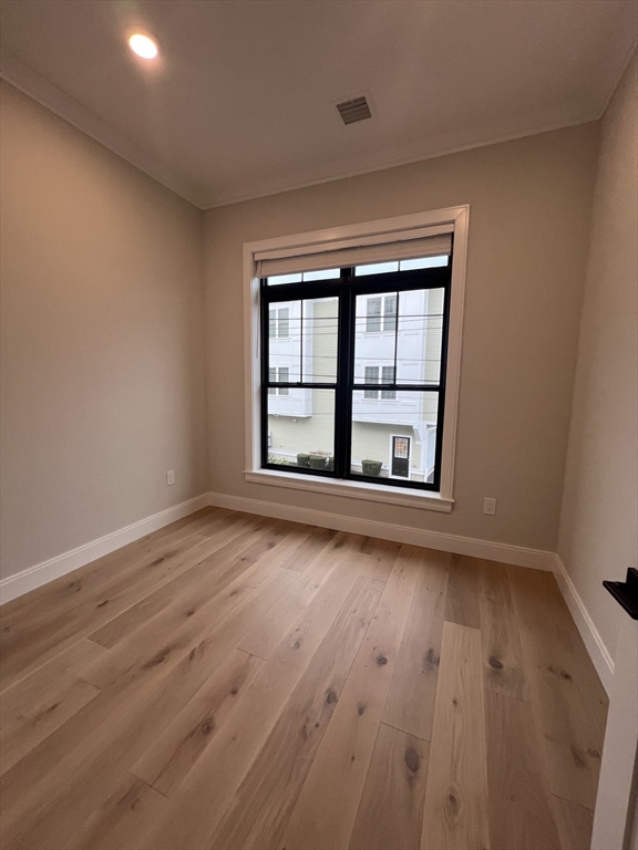 157 Everett Street, Unit 203 Boston, MA 02134 - Photo 10 of 11 an empty room with wooden floor and windows