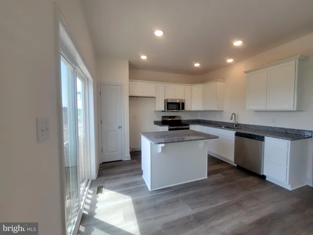 a kitchen with granite countertop white cabinets and black appliances