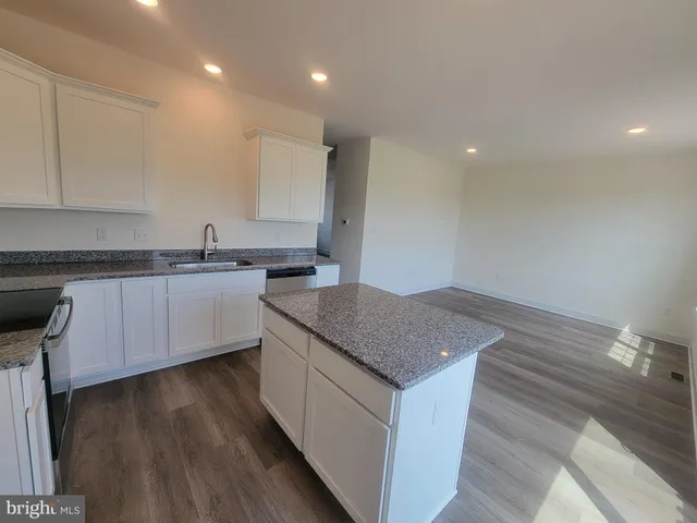 a kitchen that has a sink a microwave oven a stove and white cabinets with wooden floor