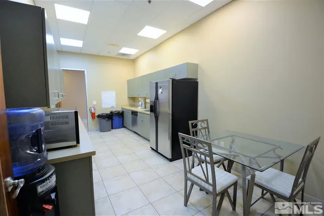 a kitchen with a refrigerator a stove top oven a dining table and chairs