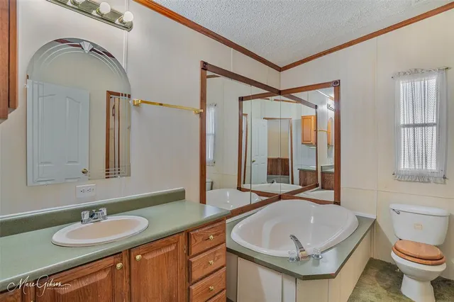 a bathroom with a granite countertop sink a toilet a mirror and shower