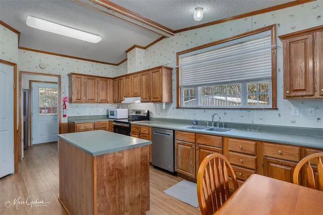 a kitchen with stainless steel appliances granite countertop a sink dishwasher stove refrigerator and cabinets
