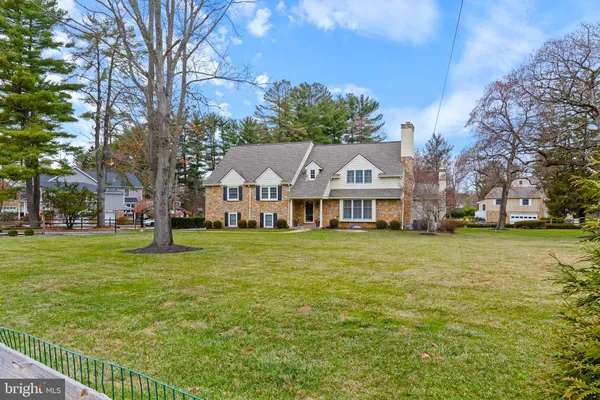 a view of a house with a big yard with large trees and a big yard with table and chairs