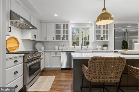 a large kitchen with granite countertop a sink and white cabinets